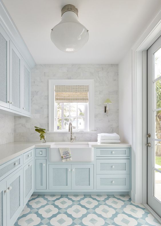 a heavenly beautiful pastel blue kitchen with rattan facades, a white countertop, a white marble tile backsplash and a blue floor