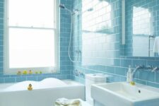 a light blue subway tile clad bathroom with white fixtures and appliances, yellow ducks for fun