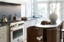 a lovely Scandinavian kitchen dove grey cabinets, a matte black backsplash, a ridged curved kitchen island and pendant lamps over it