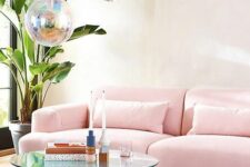 a lovely living room with a geo print wall, a pink sofa, a pink rug, a holographic table, matching pendant lamps