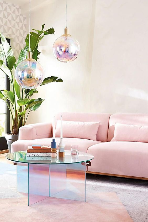 a lovely living room with a geo print wall, a pink sofa, a pink rug, a holographic table, matching pendant lamps
