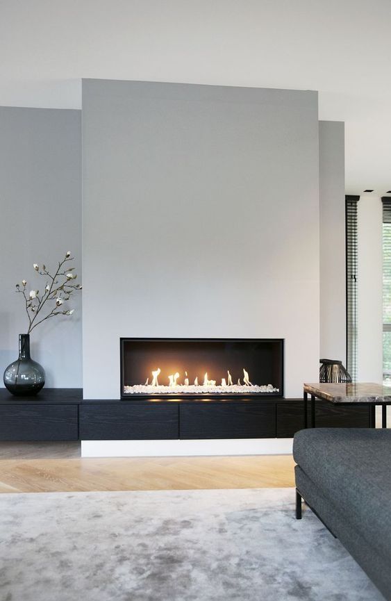a minimal living room with an ethanol fireplace, a marble side table, a grey sofa and some decor
