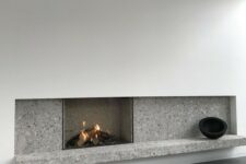 a minimalist fireplace with white paneling and grey stone plus some black touches for drama