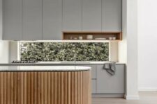 a minimalist grey kitchen with a window backsplash and a curved fluted kitchen island with a terrazzo countertop looks ultimate