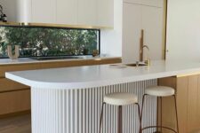 a minimalist kitchen with sleek curved cabinets, stained ones, a window backsplash, a curved fluted kitchen island and tall stools