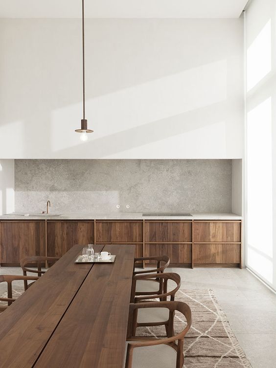 a minimalist kitchen with stained lower cabinets, a large white panel over them, a grey quartz backsplash and countertops