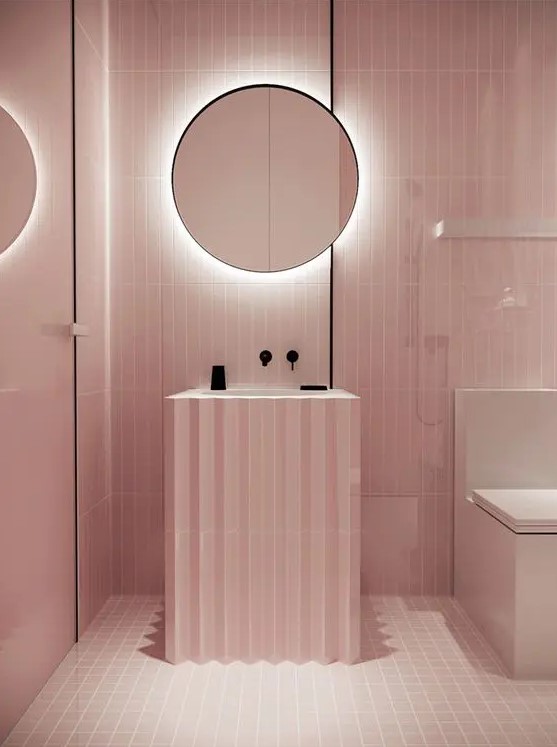 a minimalist light pink bathroom with black touches for depth and a mirror with built-in lights