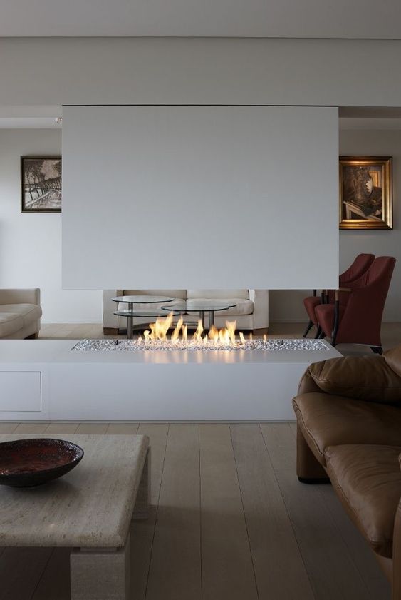 a minimalist living room with a whie ethanol fireplace, a brown leather fireplace, a low coffee table and artworks