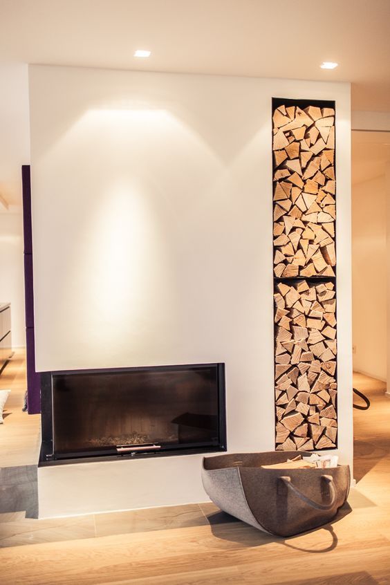 a minimalist white fireplace with a built-in niche for storing firewood is a cool idea for a contemporary or minimalist space