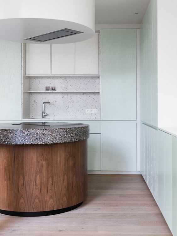 a mint green and white kitchen with a white terrazzo backsplash, a stained curved kitchen island with a stone countertop to make a statement