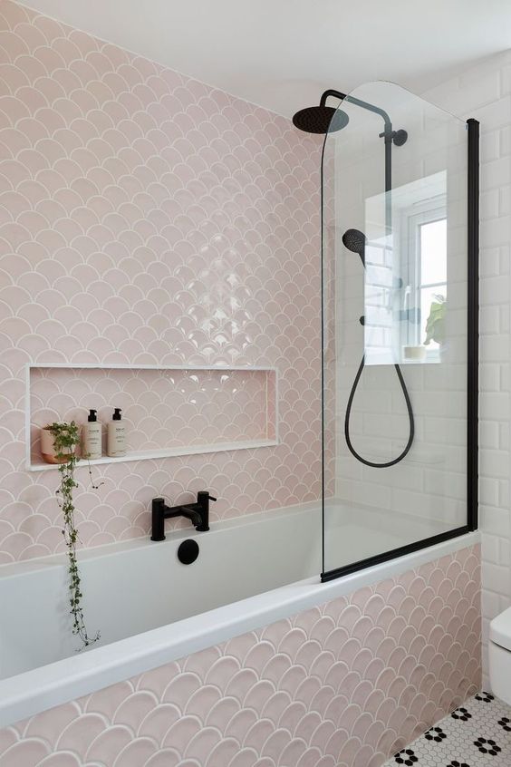 a modern bathroom in blush, white and black, with fishscale tiles, black fixtures and penny ones on the floor