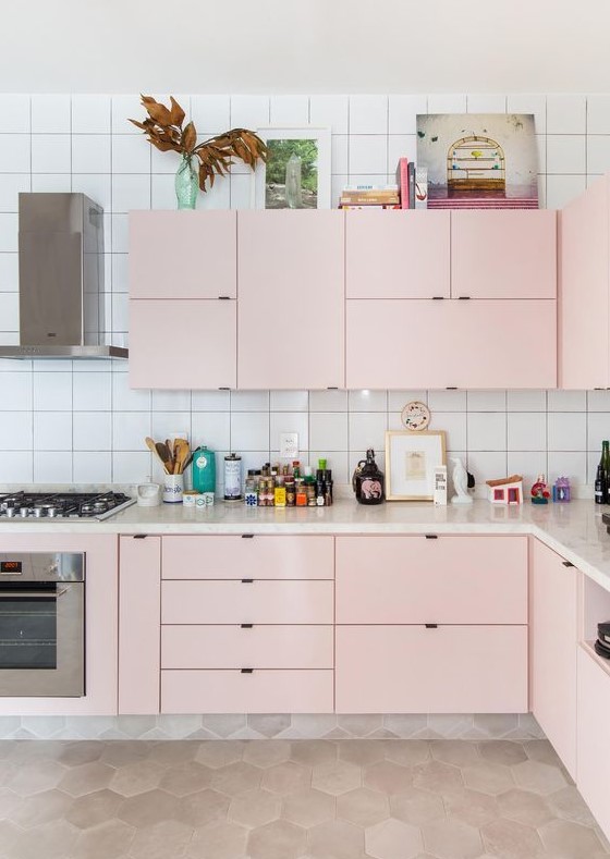 a modern kitchen in light pink, with a white tile backsplash and built-in appliances is all the chic
