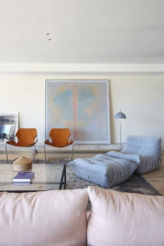  غرف معيشة بألوان الباستيل  A-modern-pastel-living-room-with-a-pink-sofa-a-dusty-blue-chair-a-footrest-a-glass-coffee-table-leather-chair