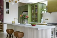 a mustard and green kitchen with usual and glass door cabinets, a matching hood, a white fluted kitchen island with a stone countertop