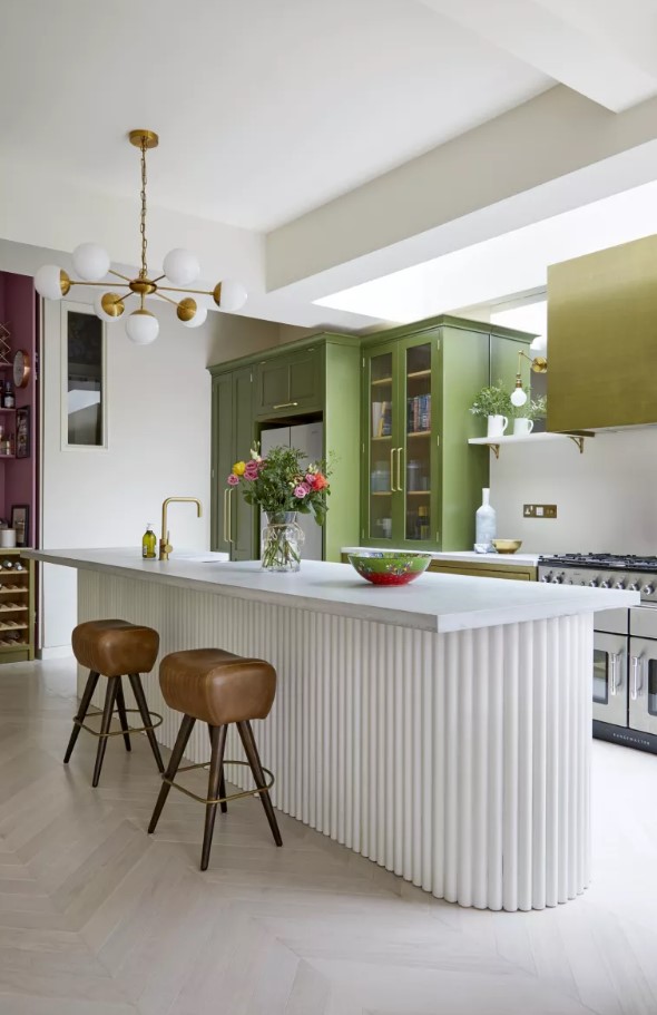 a mustard and green kitchen with usual and glass door cabinets, a matching hood, a white fluted kitchen island with a stone countertop