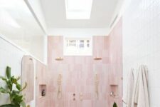 a neutral bathroom with a skylight, a pink accent wall, a floating vanity, pink sinks and potted plants