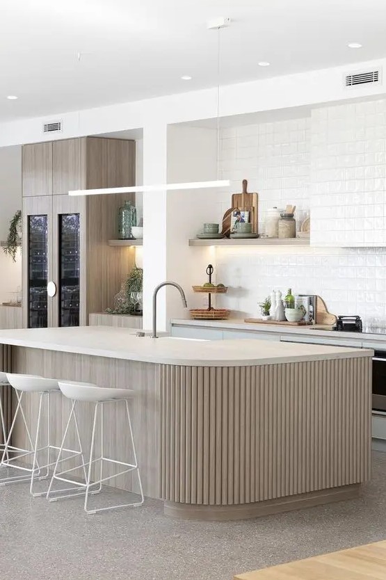 a neutral contemporary kitchen with light blue cabinets, a backsplash and a hood covered with white textural tiles and a ribbed kitchen island