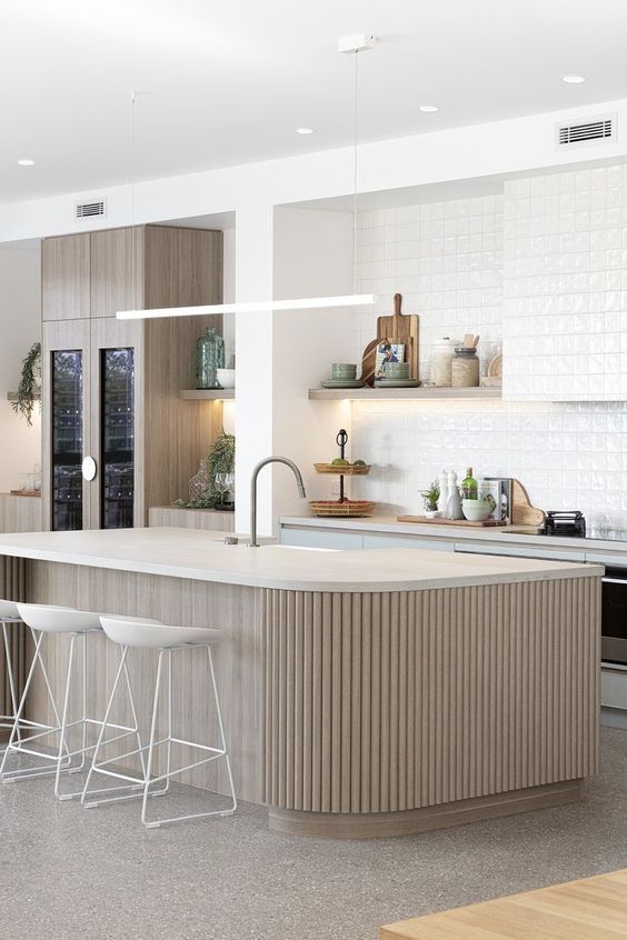 a neutral contemporary kitchen with light blue cabinets, a backsplash and a hood covered with white textural tiles and a ribbed kitchen island