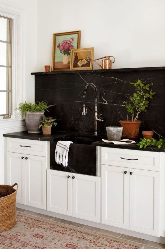 a neutral farmhouse kitchen with a black marble backsplash and countertops plus a black built-in sink