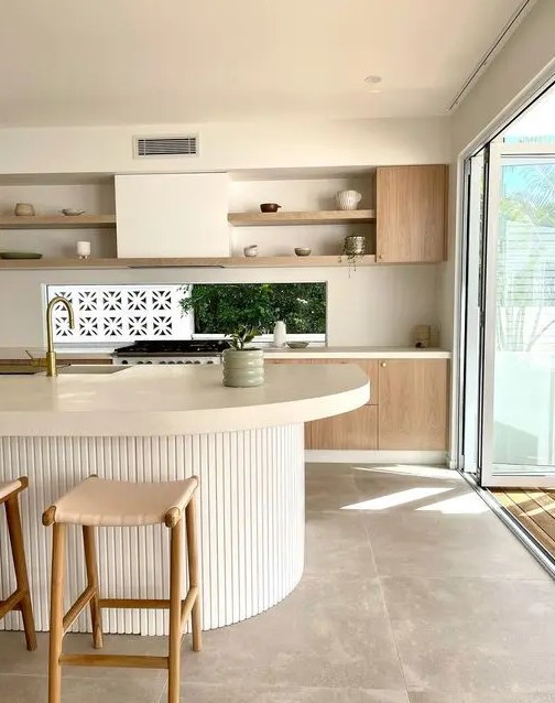 a neutral kitchen with stained cabinets, open shelves, a window backsplash and a ribbed curved kitchen island with a thick countertop