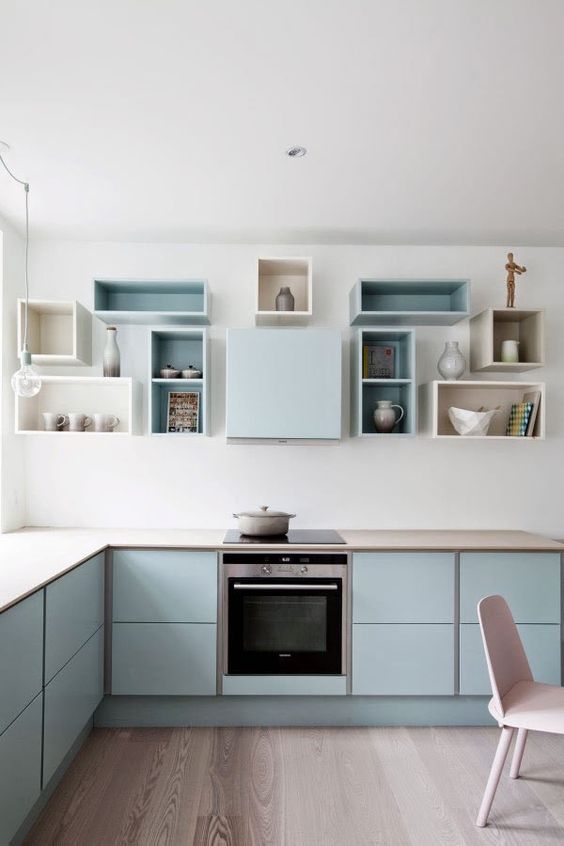 a pastel blue Scandinavian kitchen with sleek cabinets, box shelves on the wall and built-in appliances