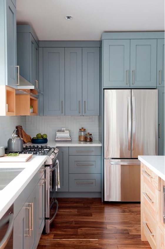 a pastel blue shaker style kitchen with a white square tile backsplash, white countertops and stainless steel handles is super chic and airy