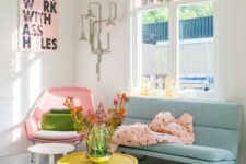 a pastel living room with a pink chair, a blue sofa with green legs, a yellow table, a pink blanket and a pink artwork