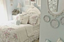 a pastel shabby chic bedroom with blue walls, shutters, plates, a mirror, floral bedding and a gallery wall