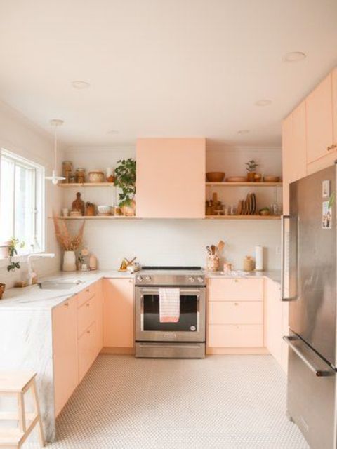 a peachy pink kitchen with plywood facades, a white stone countertop and a backsplash, open shelves and potted plants