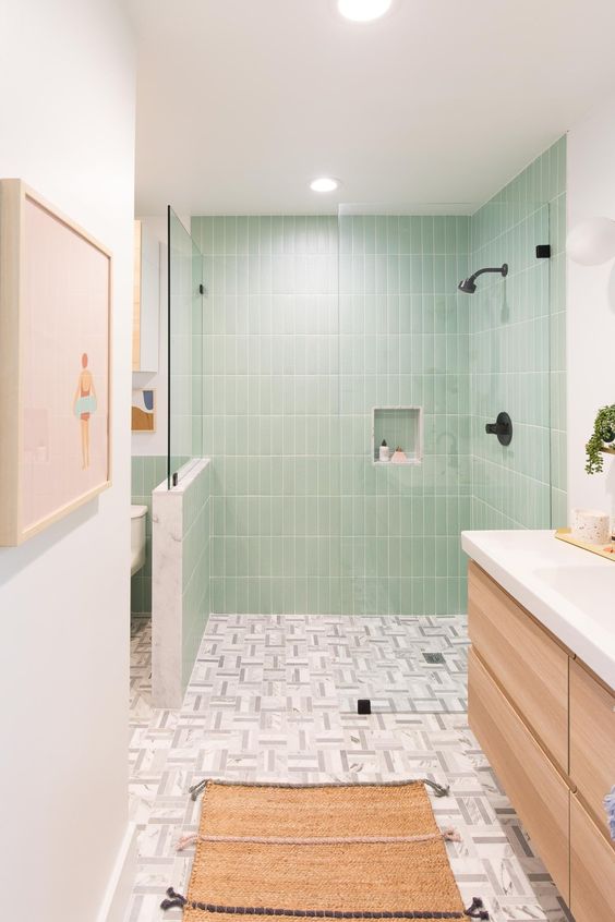 a pretty bathroom with green skinny tiles, a floating vanity, a woven rug and black fixtures
