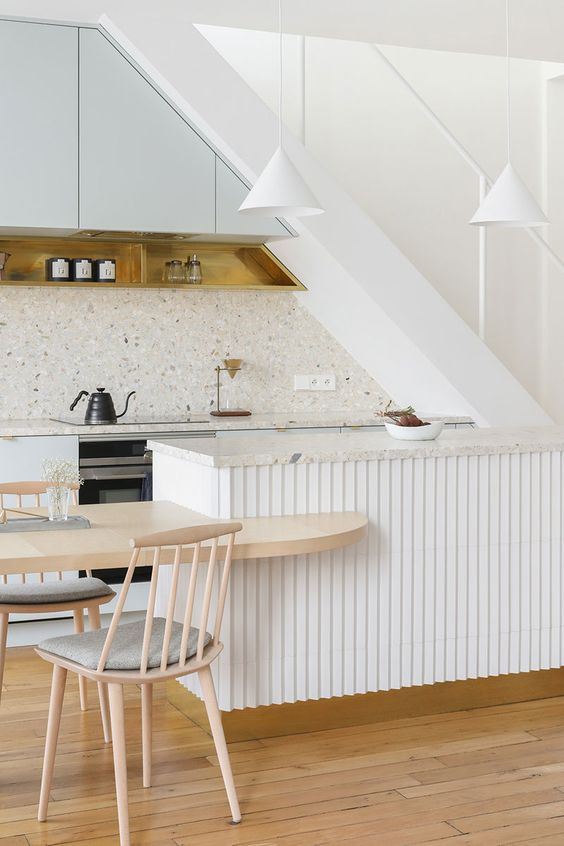 a pretty neutral kitchen sleek pale blue cabinets, an additional open shelf, a white ribbed kitchen island, white pendant lamps