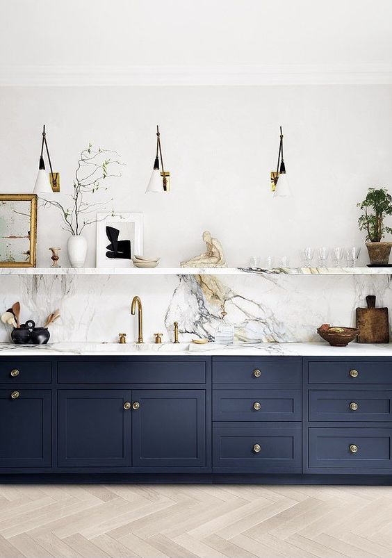 a refined navy kitchen with shaker cabinets, a white quartz backsplash and countertops, chic and cool sconces