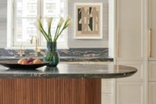 a refined vintage-inspired kitchen with creamy shaker style cabinets, a stained fluted kitchen island and black marble countertops