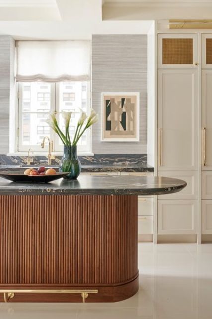 a refined vintage-inspired kitchen with creamy shaker style cabinets, a stained fluted kitchen island and black marble countertops