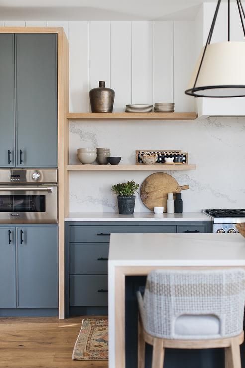 a slate grey kitchen with sleek cabinets, a white quartz backsplash and countertops, open shelves and black fixtures