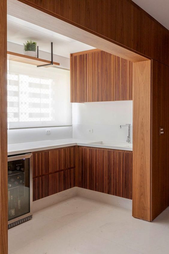 a small and cool kitchen with rich-stained ribbed kitchen cabinets, white countertops and a backsplash is amazing