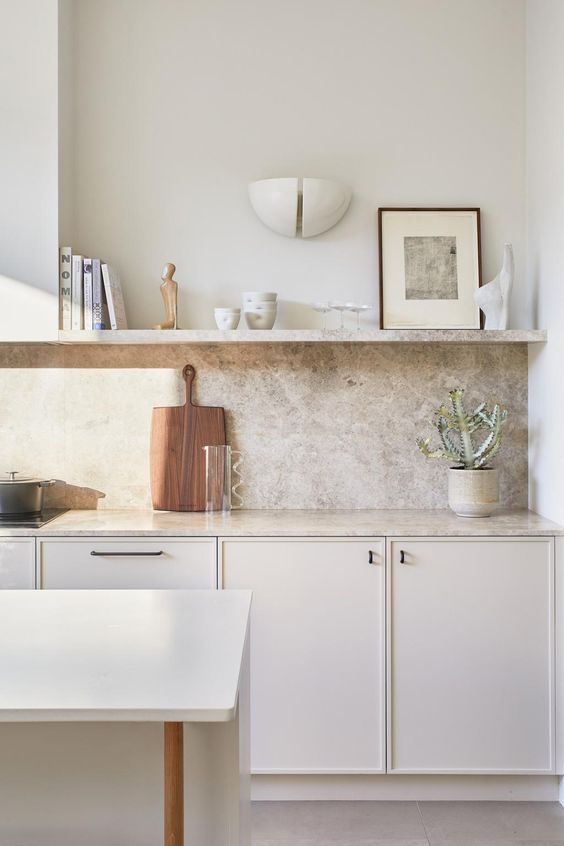 a small and elegant creamy kitchen with a grey quartz backsplash and countertops plus an open shelf is amazing