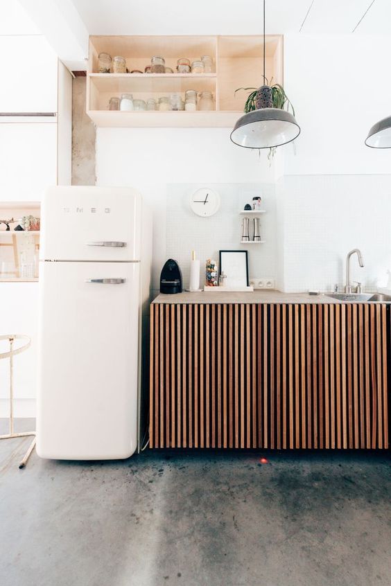a small relaxed kitchen with ribbed cabinets, a niche-like storage unit as an upper cabinet and a Smeg fridge