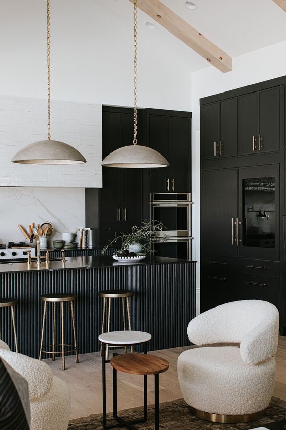 a sophisticated black and white kitchen with black and white cabinets, a black fluted kitchen island and gorgeous metal lamps hanging on chain