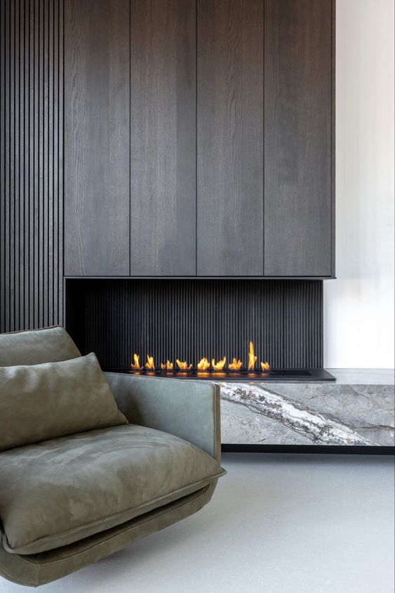 a sophisticated minimalist space with a dark wood fireplace and a grey marble slab, a grey low chair