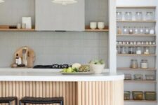 a stylish grey kitchen clad with skinny tile, with an open shelf instead of upper cabinets, an open pantry, a fluted curved kitchen island with a white stone countertop