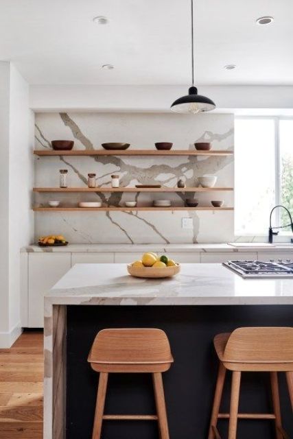 a stylish white kitchen with a navy kitchen island, a white quartz backsplash and countertops and open shelves