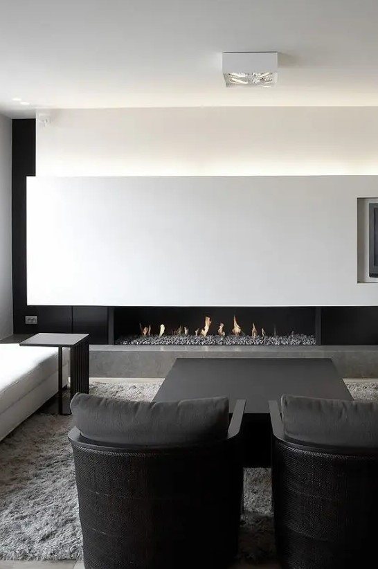 a super elegant black and white minimalist living room with a lit up wall, a fireplace, comfortable black and white furniture