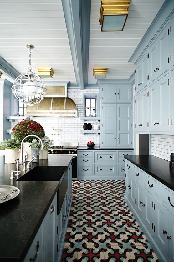 a vintage-inspired light blue kitchen with black countertops, a white tile backsplash, potted plants and a vintage hood