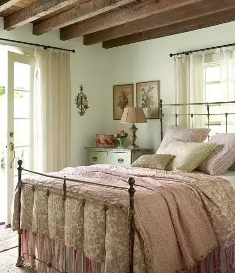 a vintage meets farmhouse bedroom with mint walls, wooden beams on the ceiling and floral print bedding