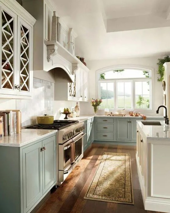a vintage two-tone kitchen with white and aqua-colored cabinets, white stone countertops and a backsplash is a chic space