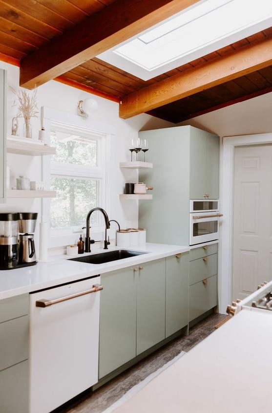 a welcoming mid-century modern kitchen in light green, a skylight, a stained wood ceiling, white stone countertops