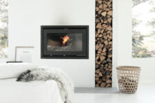 a white minimalist fireplace with a built-in firewood storage niche, a basket for firewood, a low white sofa