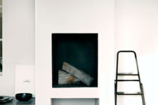 a white minimalist fireplace with firewood, a basket, a ladder and some decor around for a minimalist space