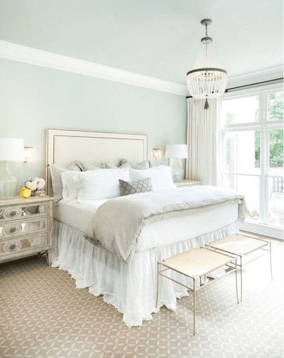 a зфыеуд glam bedroom with an upholstered bed, a crystal chandelier, mirror nightstands and elegant stools